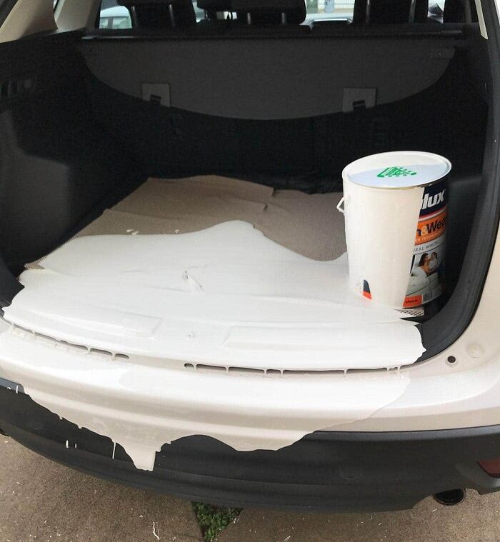 Spilled paint in the car trunk from an expensive accident, with a paint bucket on the side.