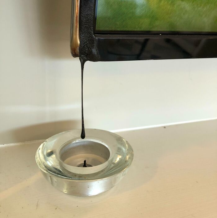 Melting TV screen dripping into a candle holder, representing an expensive accident.