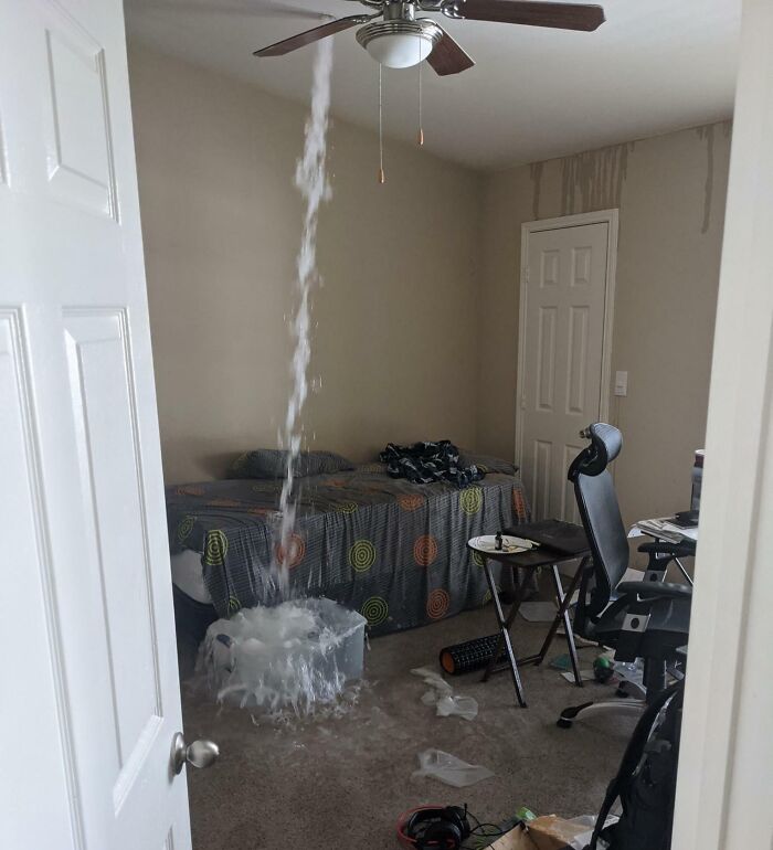 Ceiling leak in a bedroom creates an expensive accident, with water pouring into a bucket on the floor.