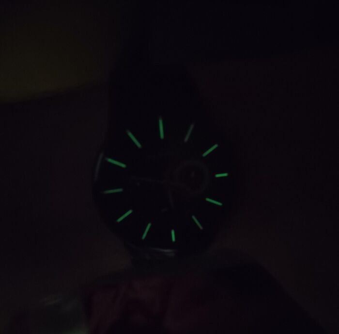 "Dark watch face with glowing green hour markers, showcasing a design fail."