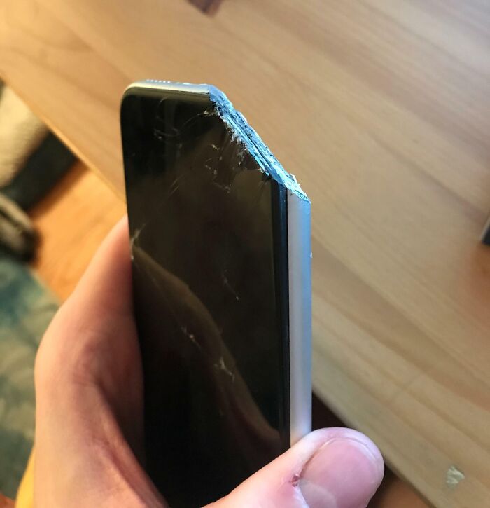 Damaged smartphone corner after an expensive accident, showing visible cracks and dents.