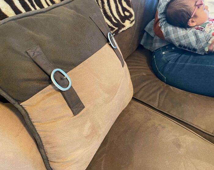 Couch with mismatched cushion design fail and a person sitting beside with a child.