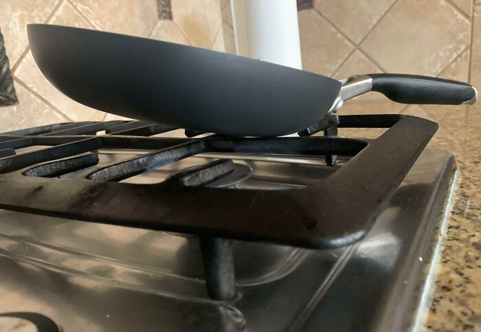 Pan design fail showing a pan unevenly balanced on a stovetop burner.