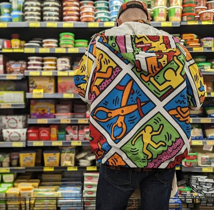 Person in a colorful jacket stands in a grocery aisle, capturing San Francisco's essence through vibrant urban style.