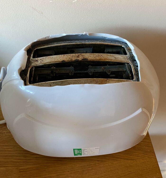 Damaged toaster on a wooden table showcasing a design fail.
