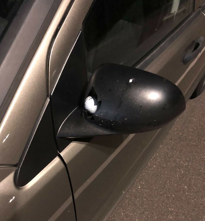 Car mirror damaged by a golf ball, illustrating an expensive accident.
