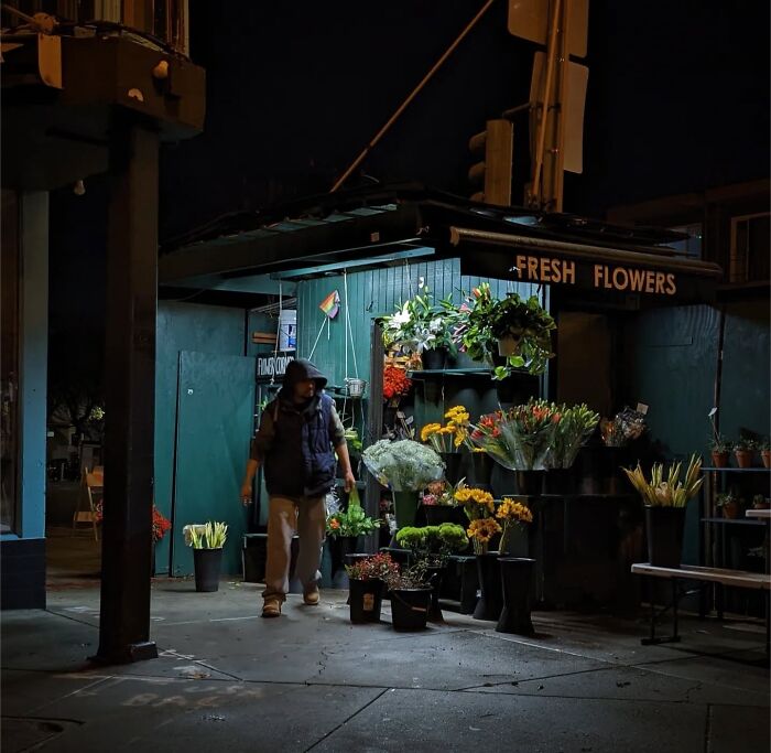 A man walks past a small flower shop in San Francisco, captured by photographer Sage Akaboshi at night.
