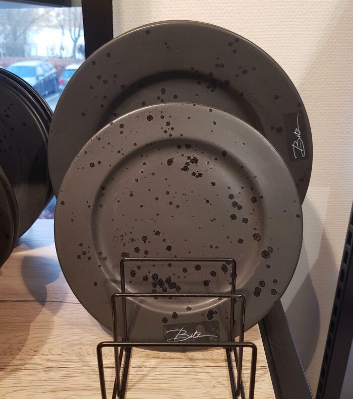 Speckled design fail on black plates with an unintended stained look, on display.