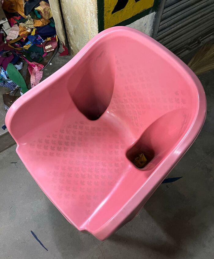 Pink plastic chair with flawed design causing instability.