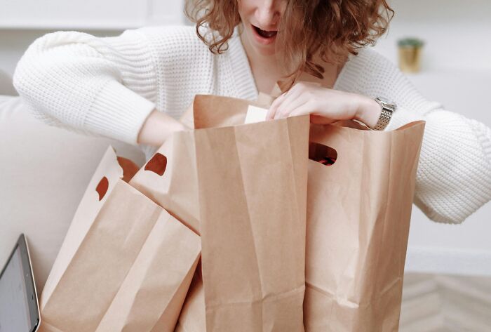 Person smiling while unpacking paper bags, showcasing simple approaches to enhance daily life.