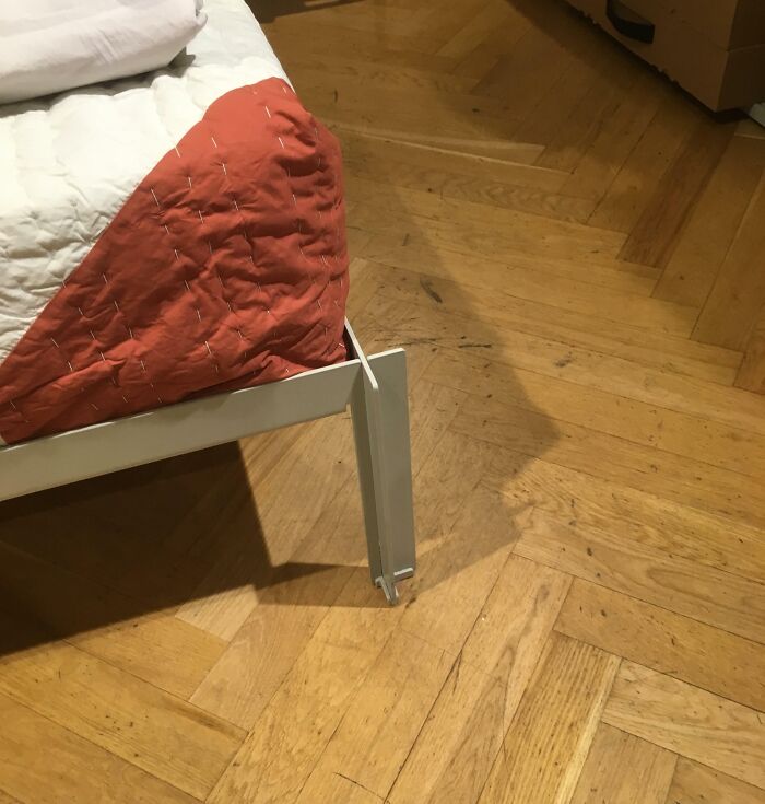 Bed frame design fail with misaligned corner, highlighting humorous error on hardwood floor.