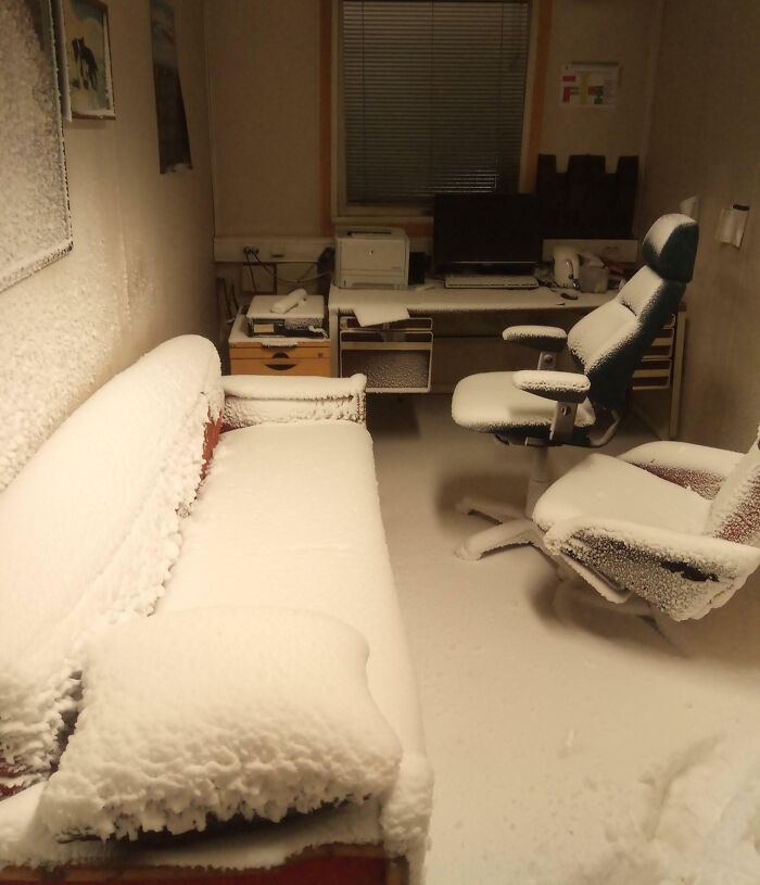 Office covered in snow due to an expensive accident, showing a snowy couch, chair, desk, and computer equipment.