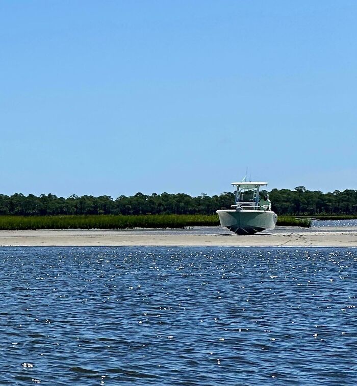 Boat stranded on sandbank, highlighting expensive accident under clear blue sky.