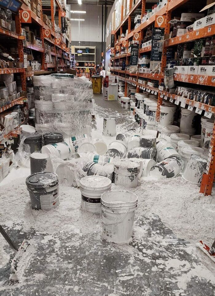 Paint cans spilled in a store aisle after an expensive accident, creating a messy and costly cleanup scene.