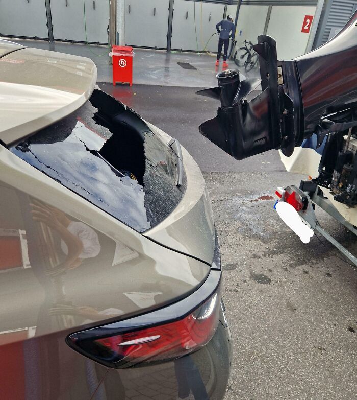 Damaged car from expensive accident involving a boat motor at a carwash.