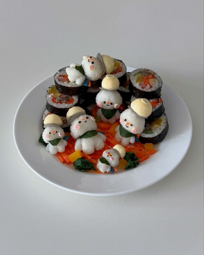 Adorable food art by a Korean artist featuring cute rice characters with sushi rolls on a white plate.
