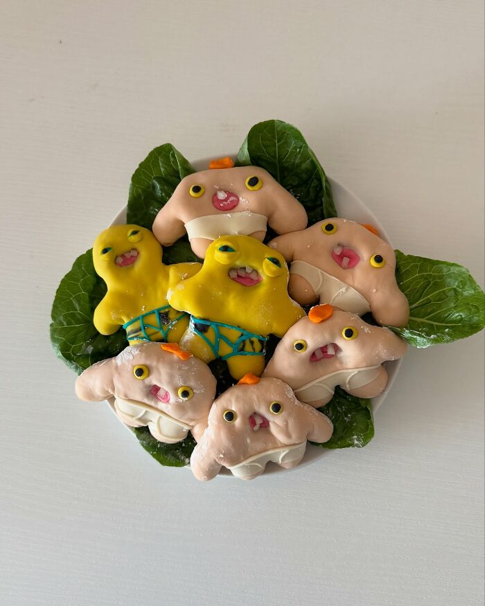 Adorable food arrangement by Korean artist featuring cute animal-shaped treats on a bed of green leaves.