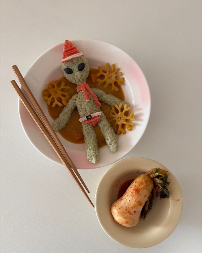 Korean artist's creative food art: rice creature in a bowl with chopsticks, alongside a bowl of radish kimchi.