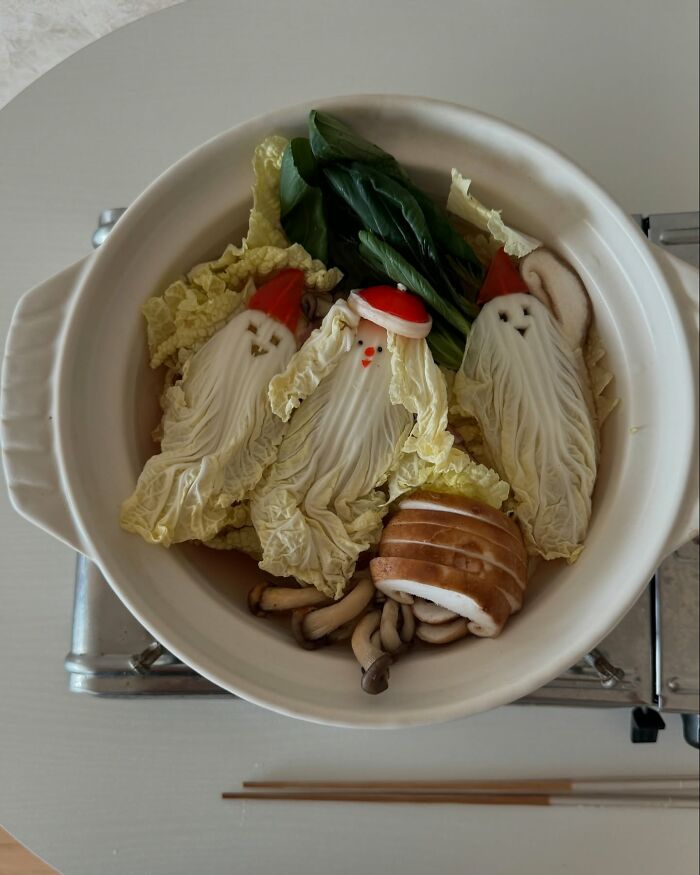 Adorable Korean food art featuring cabbage arranged as cute Santas in a pot, with mushrooms and greens.