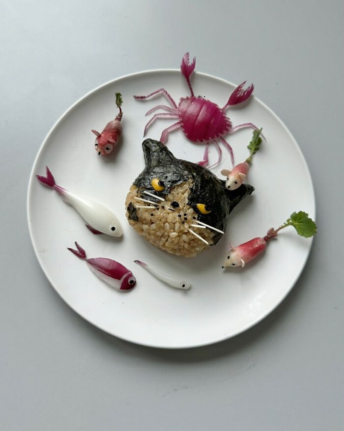 Adorable food art arranged to resemble a cat and sea creatures on a white plate by a Korean artist.