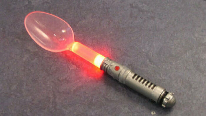 1980s-inspired spoon with a glowing neon handle on a dark surface.