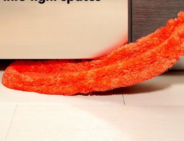 Orange fluffy draft stopper under a door, enhancing quality of life by reducing drafts.