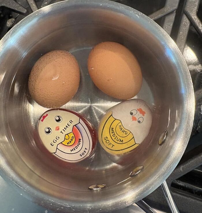 Boiling eggs with egg timers in a pot on a stove, showing cooking levels of hard, medium, and soft.