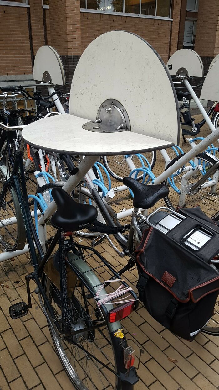 Bicycles parked in a unique stand with integrated tables, showcasing a country's innovative citizen care approach.