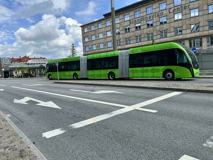 Green articulated bus at a Scandinavian Center, showcasing citizen care innovations.