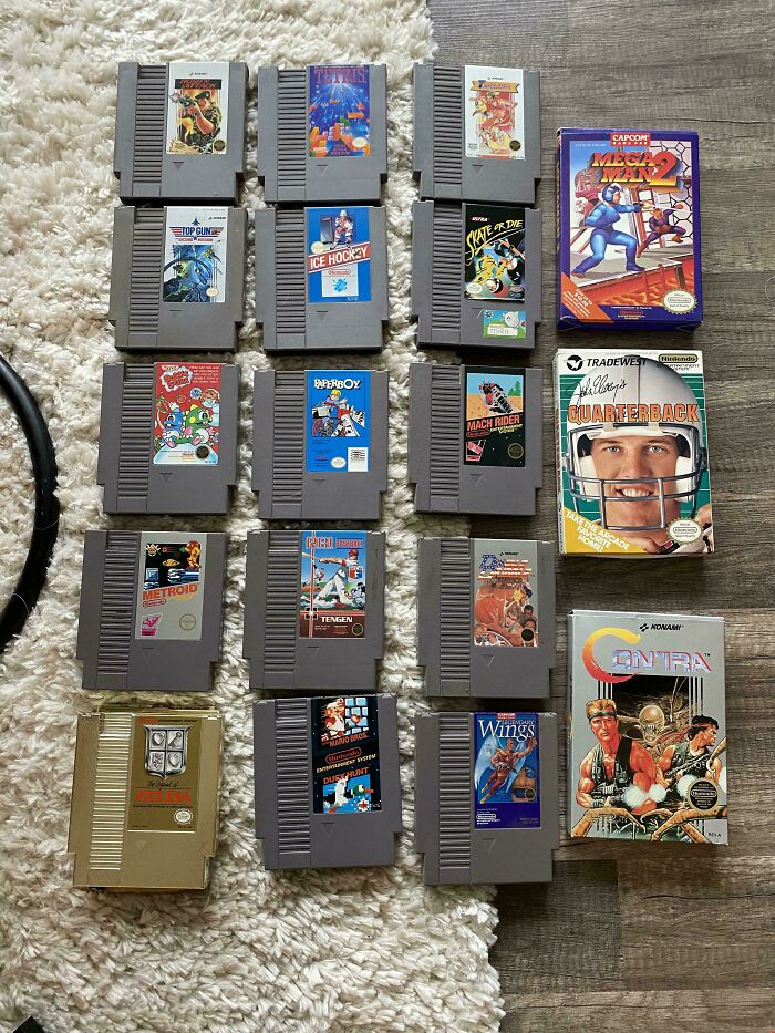 A collection of 1980s video game cartridges, including titles like "Tetris," "Metroid," and "Contra," displayed on carpet.