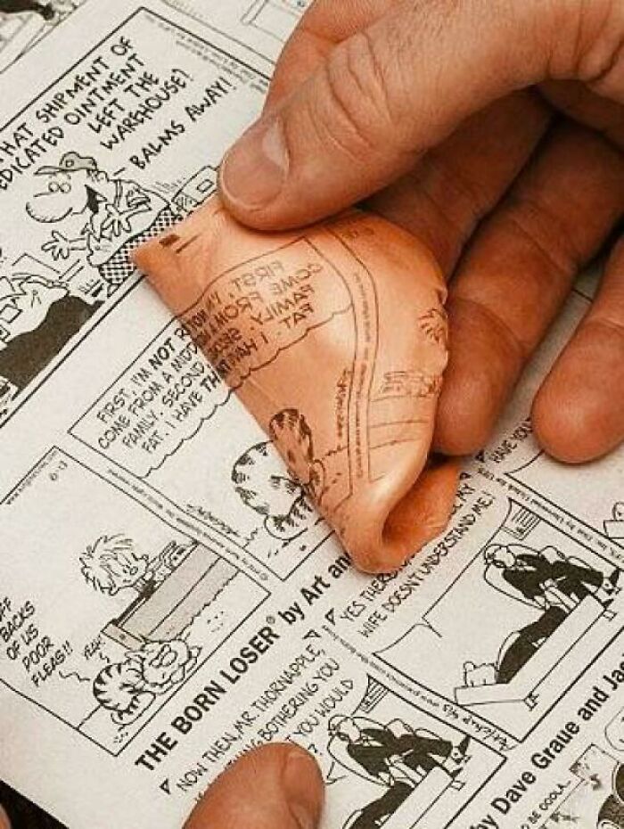 Hand peeling off vintage newspaper comic strip from a rubber eraser, nostalgic pics show old memories realized.