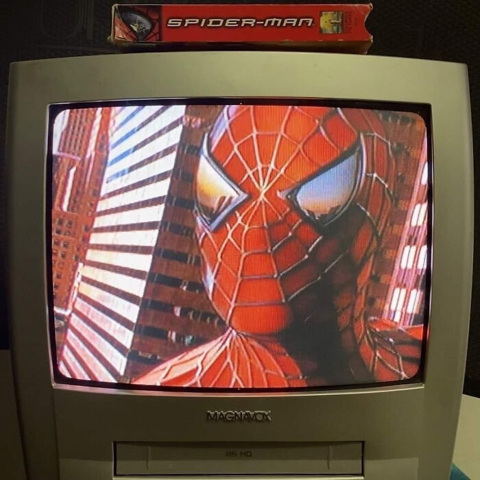 Vintage Magnavox TV displaying Spiderman, with VHS tape on top, encapsulating 1980s nostalgia.