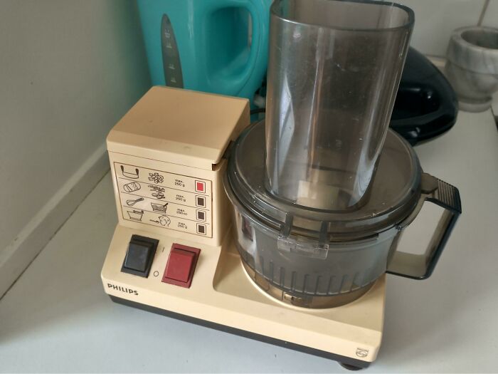1980s Philips food processor on kitchen counter with control buttons and recipe guide.