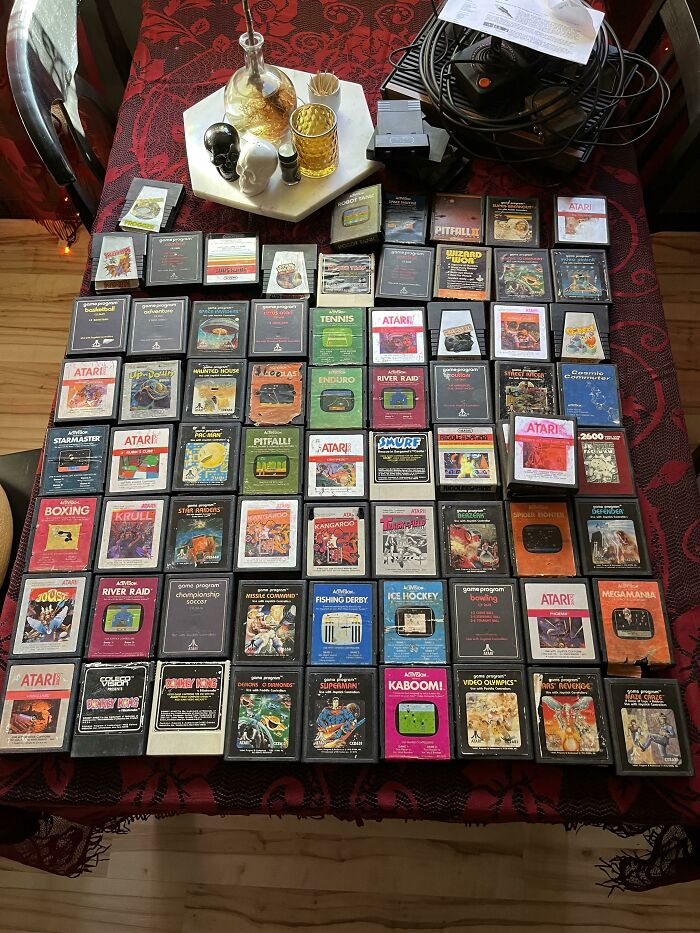 Collection of vintage 1980s Atari video game cartridges displayed on a red-patterned table.