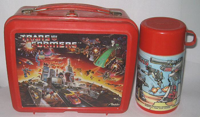 1980s Transformers lunchbox and thermos set with vibrant artwork.