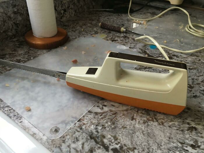 Vintage 1980s electric knife on a kitchen counter, surrounded by a few crumbs and a roll of paper towels.