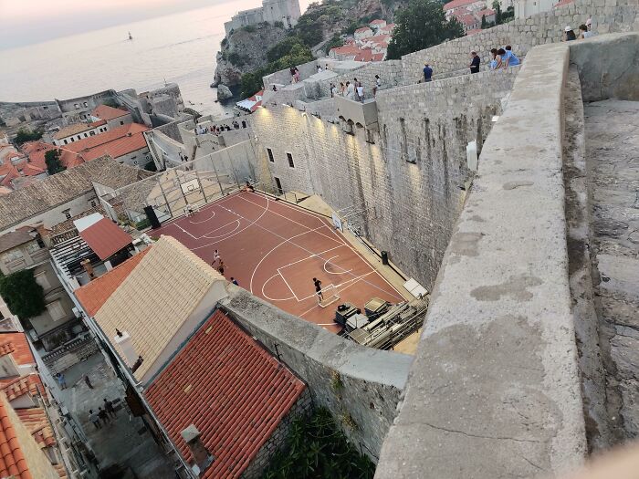 Scenic view of a basketball court nestled among iconic historic walls overlooking the sea.