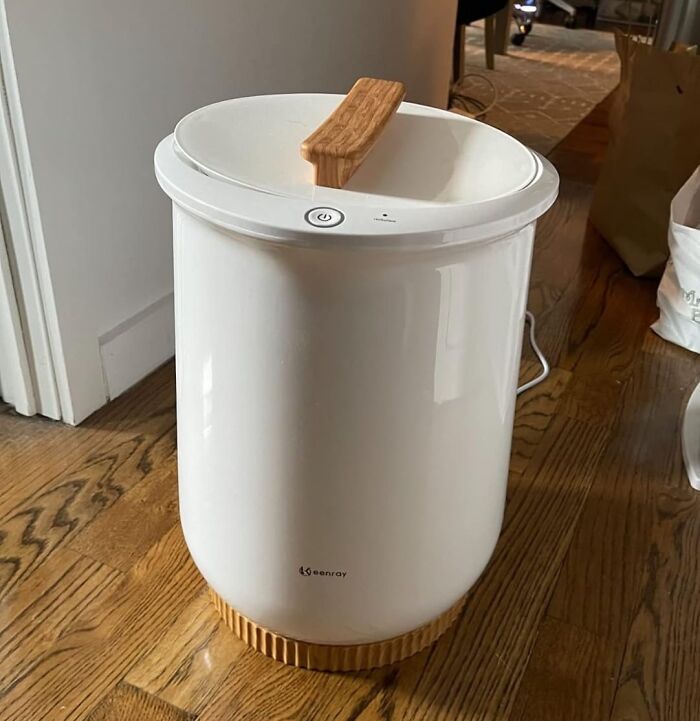 A sleek white compost bin on a wooden floor enhances quality of life by making home composting easy.