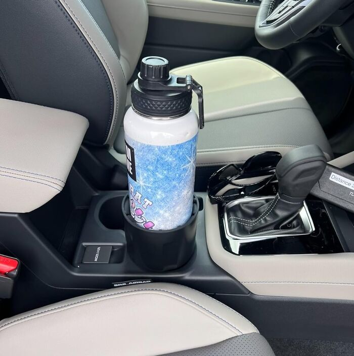 Water bottle in a car cup holder next to sunglasses, reflecting improved quality of life with organized car accessories.