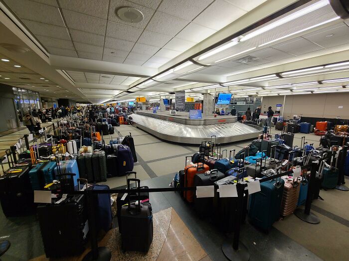 Airport baggage claim area crowded with unattended luggage, illustrating airline baggage fails.