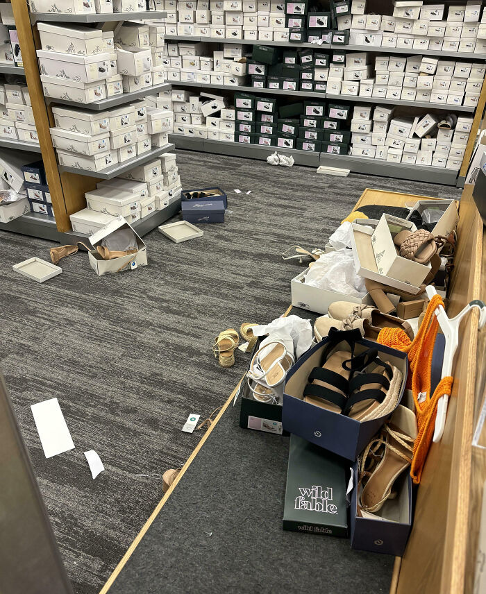 Messy shoe store aisle with scattered boxes and sandals, showcasing customer cluelessness.