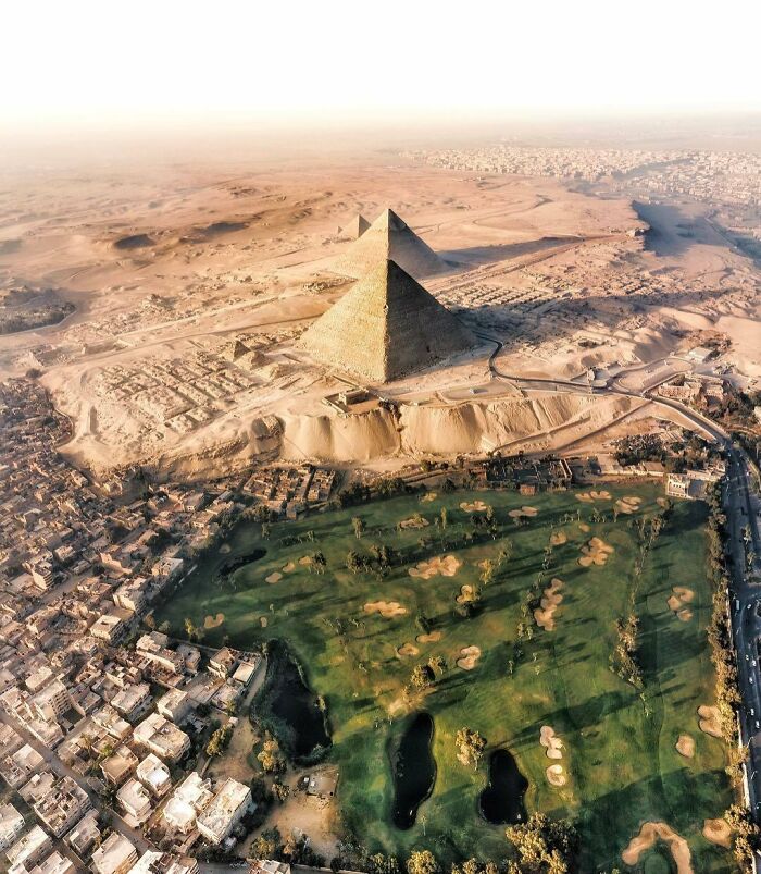 Aerial view of iconic pyramids in Egypt surrounded by desert and urban landscape.