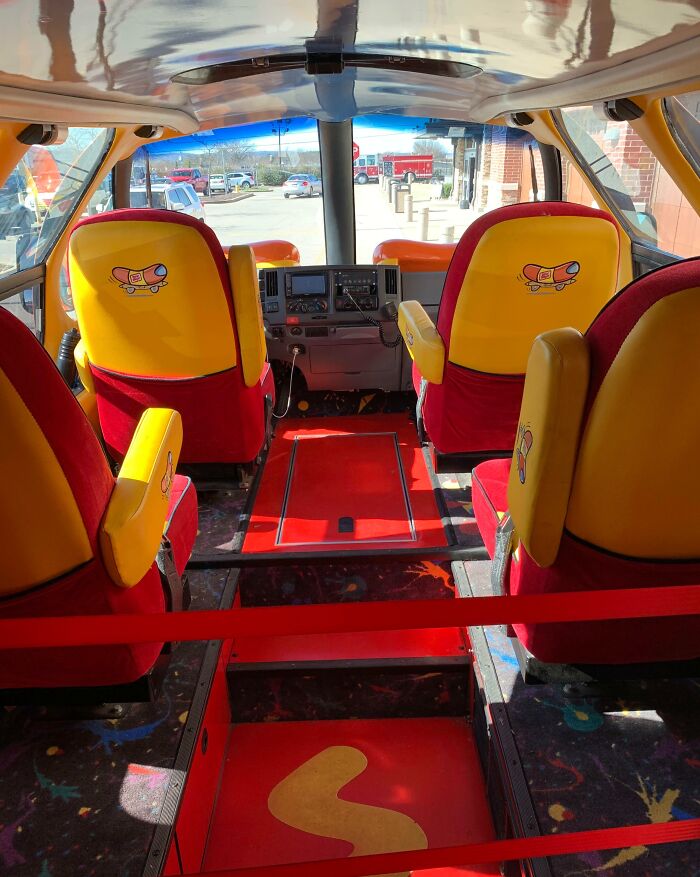 Interior of the Wienermobile with bright yellow and red seats, an awe-inspiring iconic vehicle around the world.