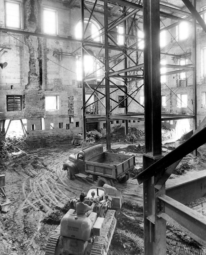 Renovation inside an iconic historic building, with construction vehicles and exposed steel beams.