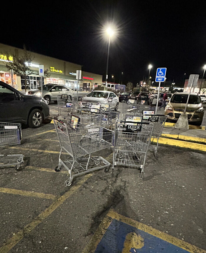 Shopping carts left in a parking space at night, highlighting customer cluelessness at a store parking lot.