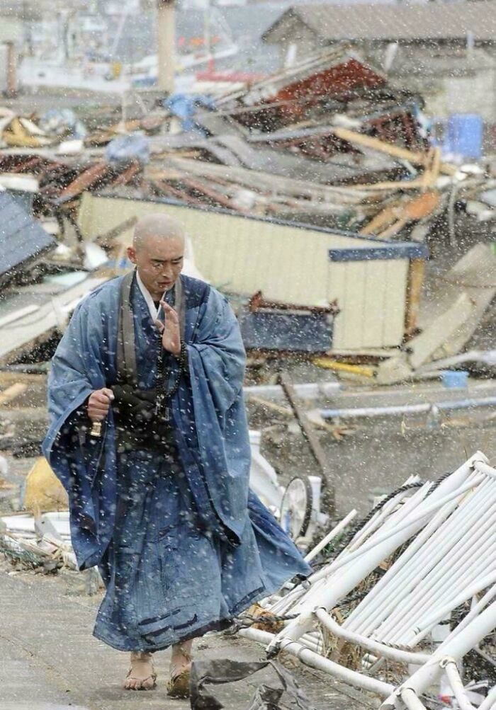 A monk in traditional robes walking barefoot through debris in falling snow, resembling a Renaissance masterpiece scene.