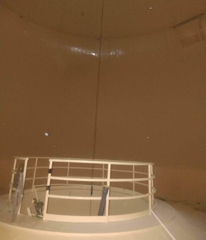 Interior of a large, empty beige structure with a central railing, showcasing iconic architectural elements.