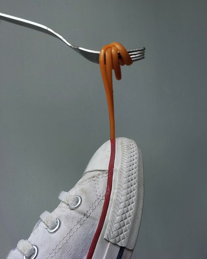 A fork twists spaghetti into a white sneaker, showcasing Dudi Ben Simon's illusion art.