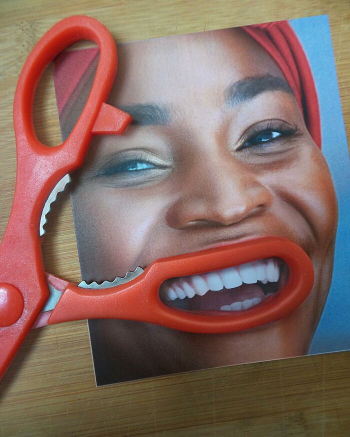 Red scissors cleverly aligned with a smiling face image, creating an illusionary fusion.