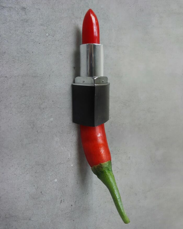 Chili pepper mimicking lipstick on a concrete background, showcasing illusion and fusion art.